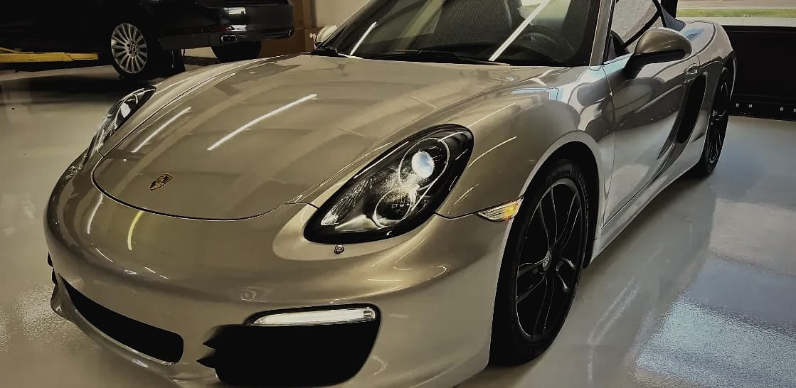 A silver Porsche on the workshop floor, seen from the front.