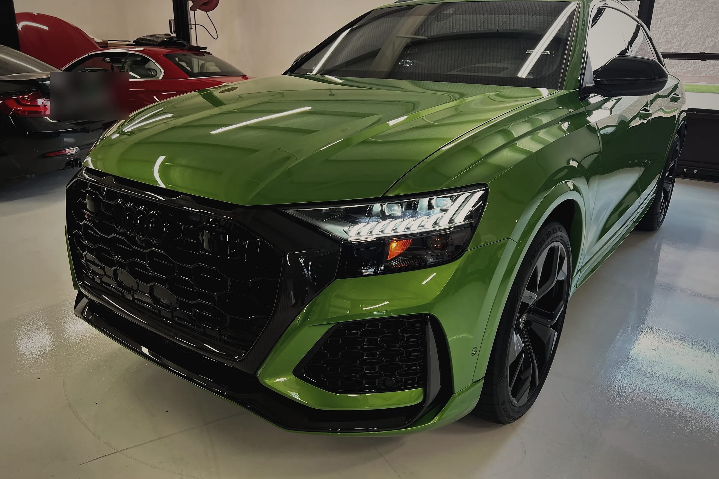 A green Audi RS Q8 on the workshop floor, seen from the front.