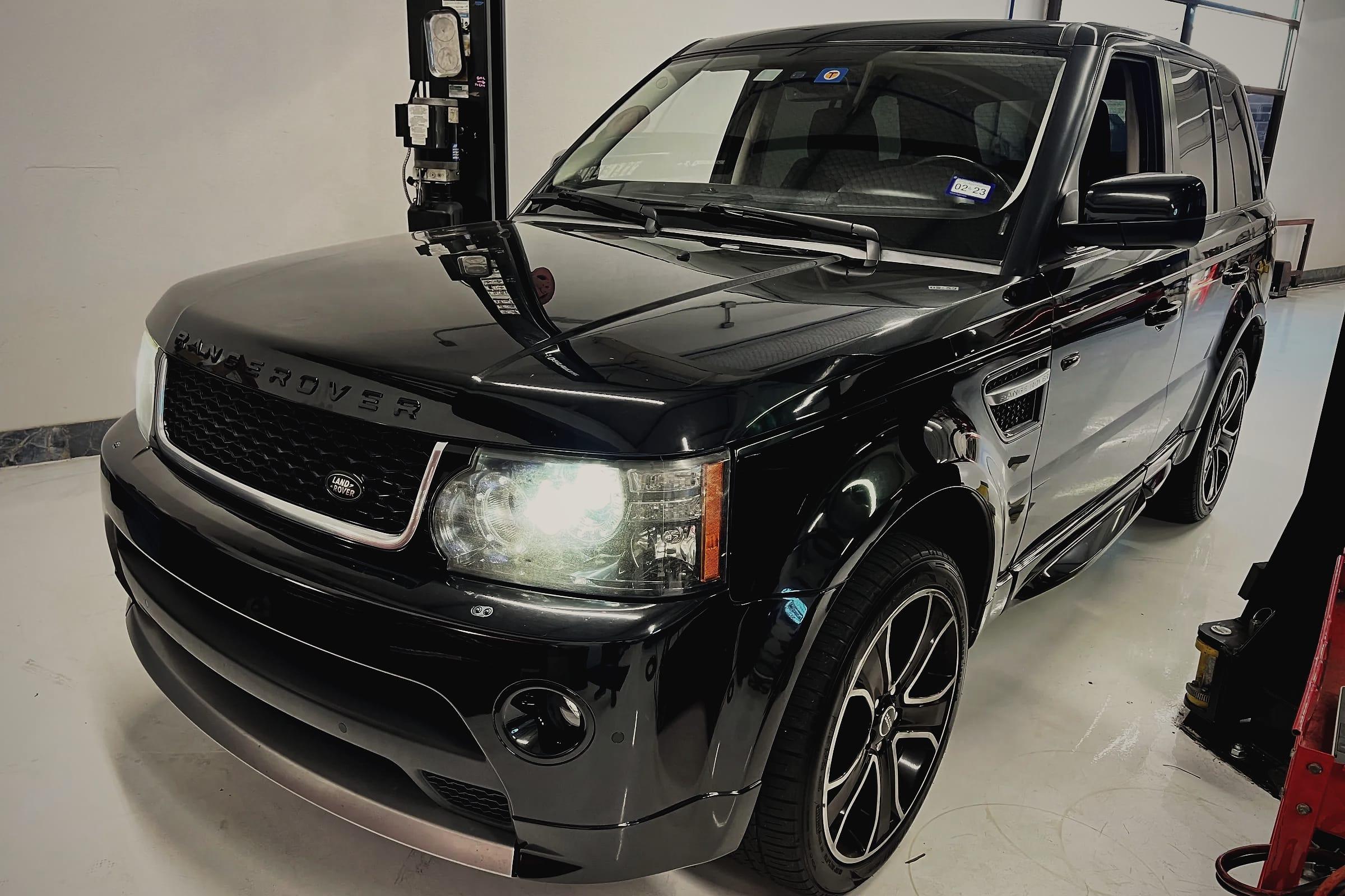 A black Range Rover Sport beside a two-post lift in the workshop.